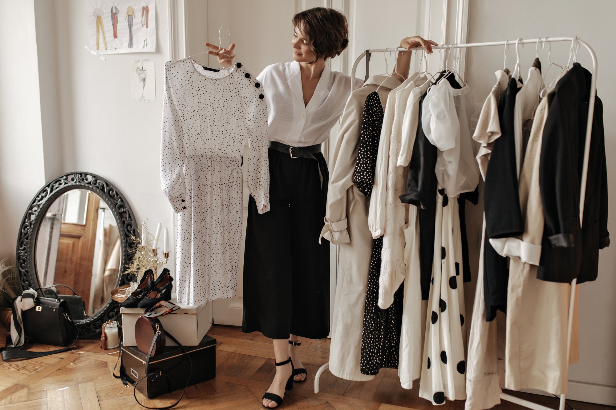 Attractive short-haired brunette woman in stylish pants, white blouse poses in dressing room and ho